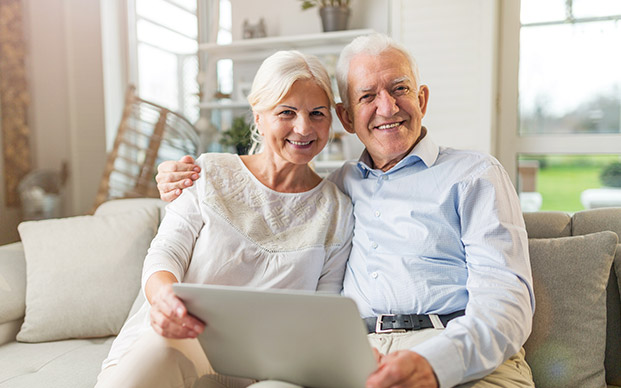Happy retirement couple holding computer